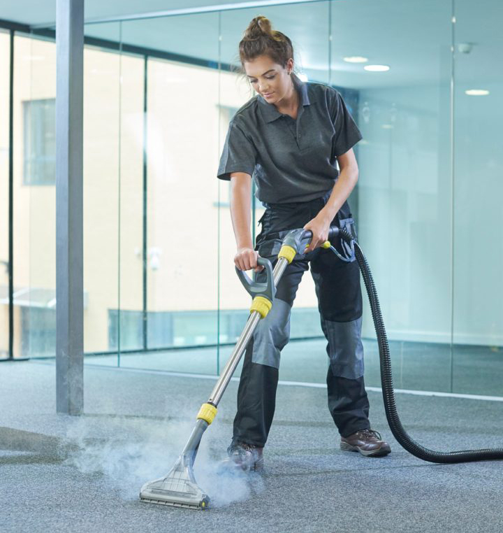 Woman steam cleaning office carpet.